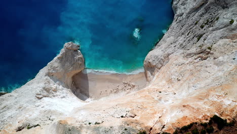 Toma-De-Drones-En-ángulo-Descendente-De-La-Pintoresca-Playa-De-Navagio-En-Zakynthos,-Con-La-Famosa-Playa-Del-Naufragio-Y-Sus-Impresionantes-Acantilados.