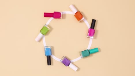 movimiento creativo de las botellas de esmalte de uñas en círculo sobre fondo beige.