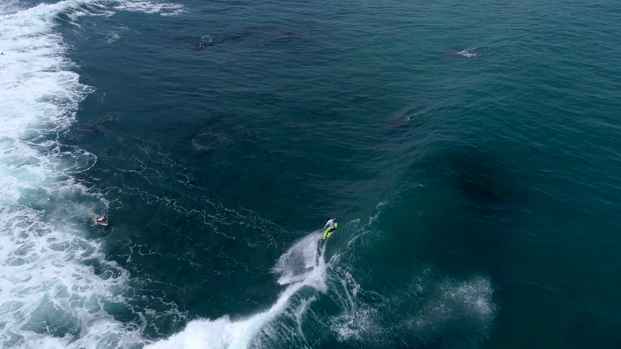 toma amplia desde la vista aérea de un dron siguiendo una ola con un surfista entrando en la toma