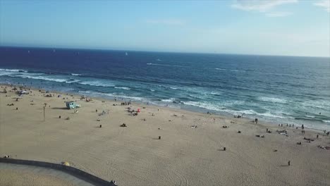 Sunny-Venice-beach-California-smooth-Drone-shot-pulling-in-over-tall-palm-tree,-revealing-beautiful-blue-beach