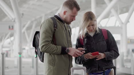 couple checking mobile phones at airport