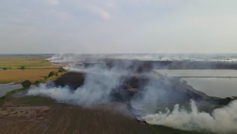 Aerial-footage-towards-burning-farmland-ready-for-the-next-panting-season-revealing-tilled-lands-and-the-horizon,-Grassland-Burning,-Pak-Pli,-Nakhon-Nayok,-Thailand