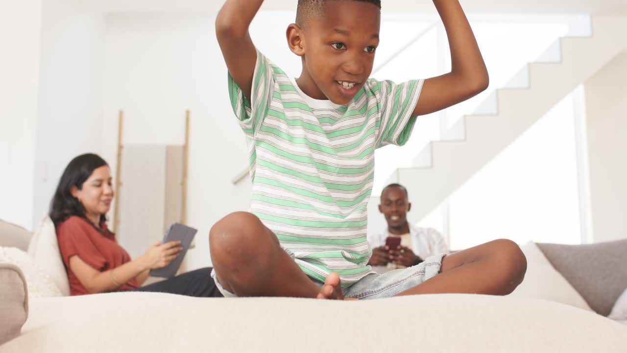 Diverse family youth sitting on couch, putting on white VR headset, exploring robot face parts