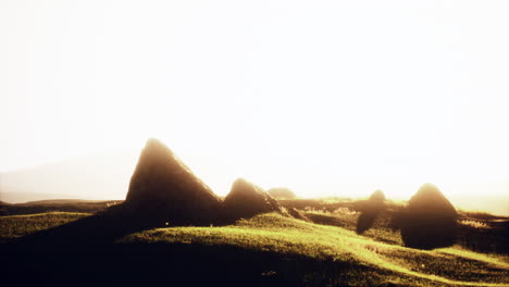 sunrise over a grassy hill with rocks