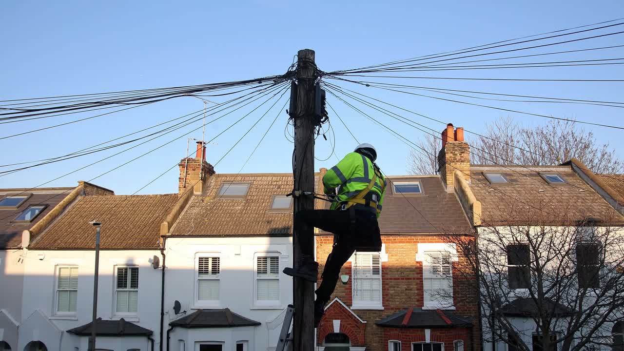 Telecommunication engineer working on cables at the top of a telephone pole