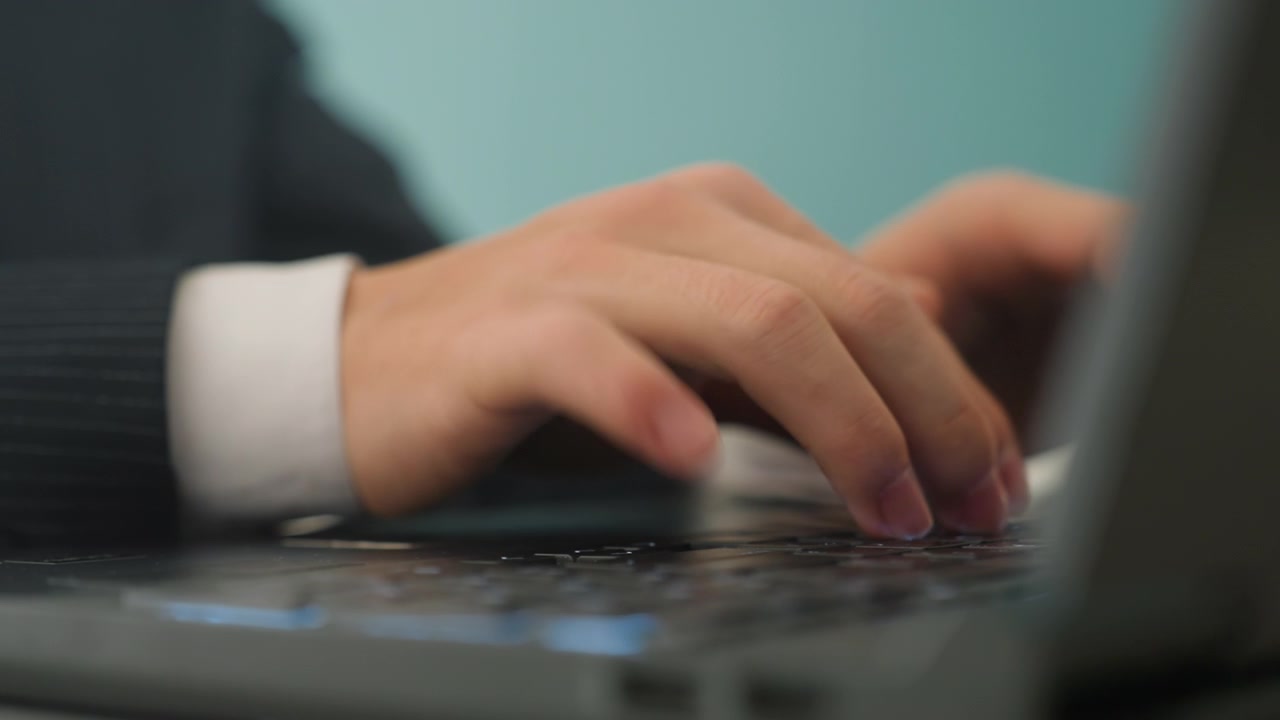 Individual diligently entering text on digital device. Person concentrated on keyboard as they complete office task. Focused individual types on computer keyboard during professional work activity