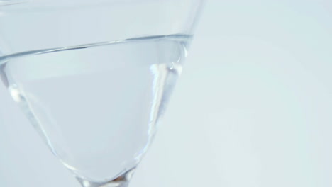 grey paper burning over close up of cocktail glass against grey background