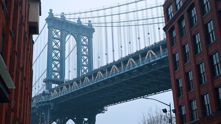 New York, USA, 25 December 2025: Manhattan Bridge framed by historic brick buildings in DUMBO Brooklyn. Iconic symmetric view of the blue Manhattan Bridge steel structure between red brick facades.