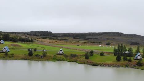 Luftaufnahme-Von-Niedlichen-Ferienhäusern-In-Der-Nähe-Eines-Sees-In-Island