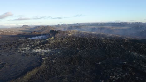 aerial backwards shot of boiling volcano crater during sunlight and blue sky - geldingadalir,iceland