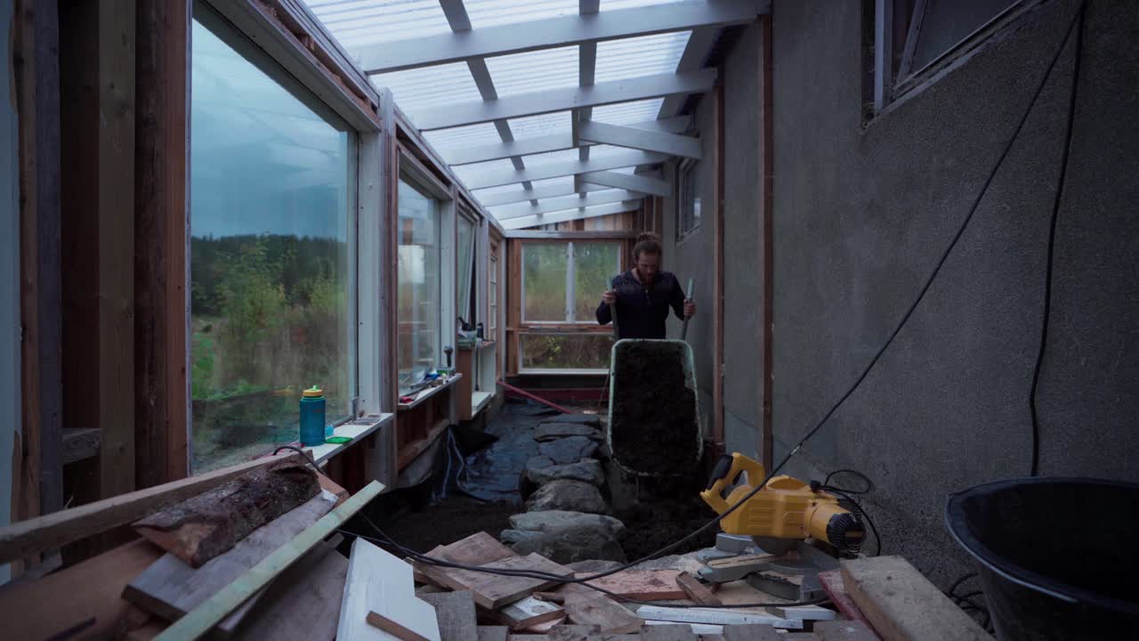 한 사람 이 온실 을 짓는 데 사용 하기 위해 바 에서  을 옮기고 있다 - 정적