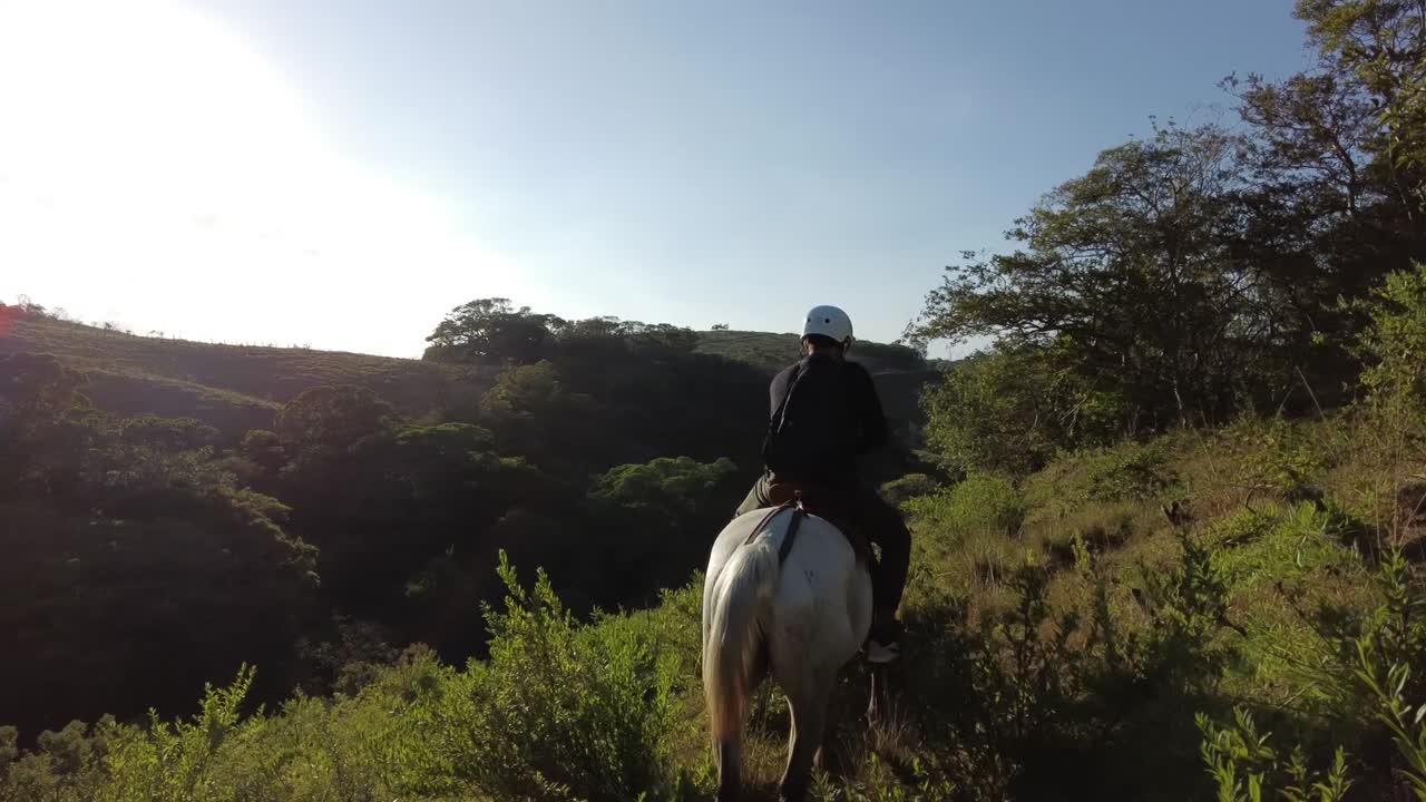 hombre adulto practicando una excursión a caballo cuesta arriba en los bosques tropicales de monteverde, costa rica, con equipo de protección y una mochila