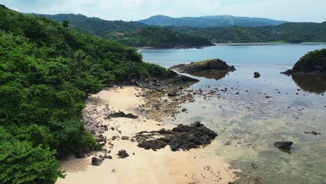 Aerial-dolly-of-white-sand,-rocky-beach-resort-and-reef-in-the-tropical-island-of-the-Philippines