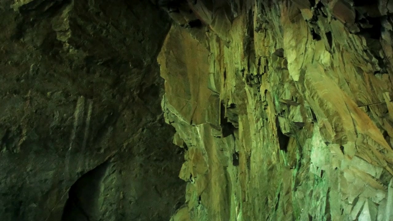 Panning shot across the towering roof of Cathedral Cavern in Little Langdale, revealing dramatic rock formations, rugged cave textures, and the vast scale of the historic underground chamber
