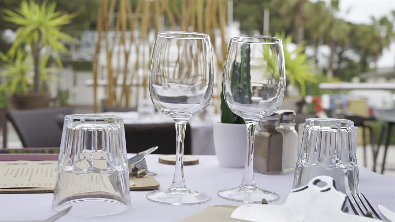 Close up of glasses on a set table at a terrace with people walking on the blurred background