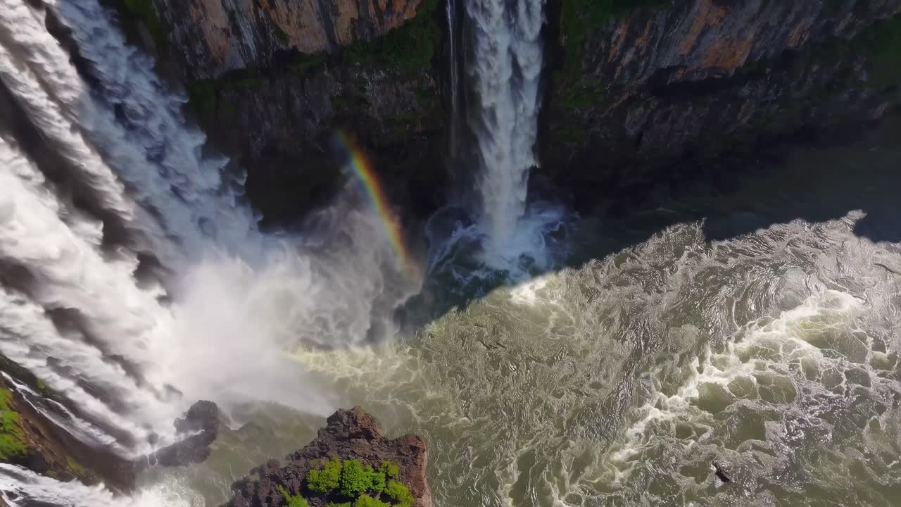 Luftvideo av en majestetisk foss som fosser nedover klipper, omgitt av frodig grønt