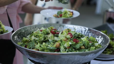 guests placing caesar salad onto their plates at wedding banquet