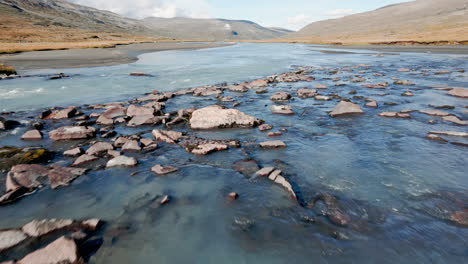 hermoso primer plano de seguimiento de un río, que fluye a través de un paisaje pedregoso y estéril, día soleado, luz del día, sin gente