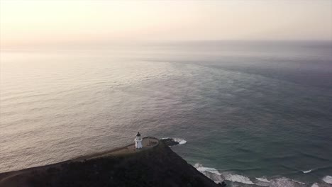 Leuchtturm-Von-Cape-Reinga-An-Der-Küste-Bei-Sonnenuntergang,-Schwenk-Drohnenaufnahme-–-Neuseeland