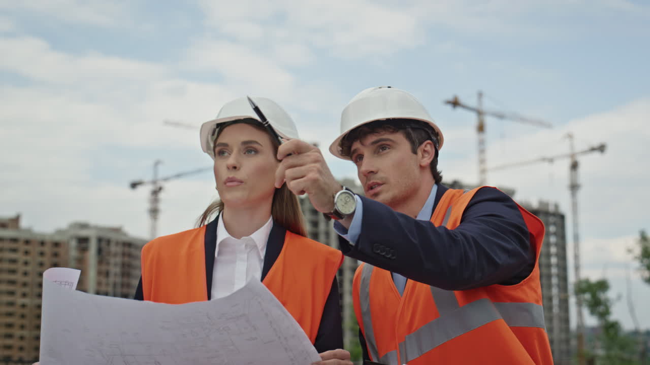Engineers review construction plans together at outdoor building site closeup