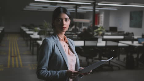 professional businesswoman standing in a modern office with documents