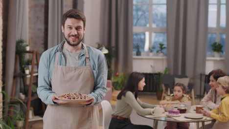 man holding a pie with family at a table