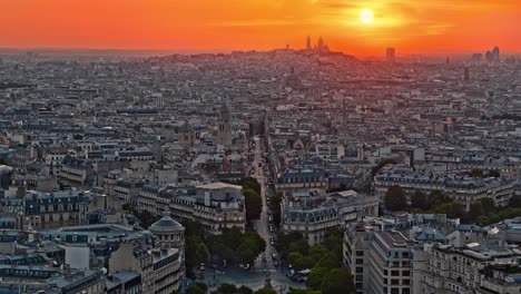 aerial drone footage of frances central city paris during vibrant orange sunset or sunrise during dusk or dawn with skyscrapers, small buildings and road beneath where cars and vehicles are driving.