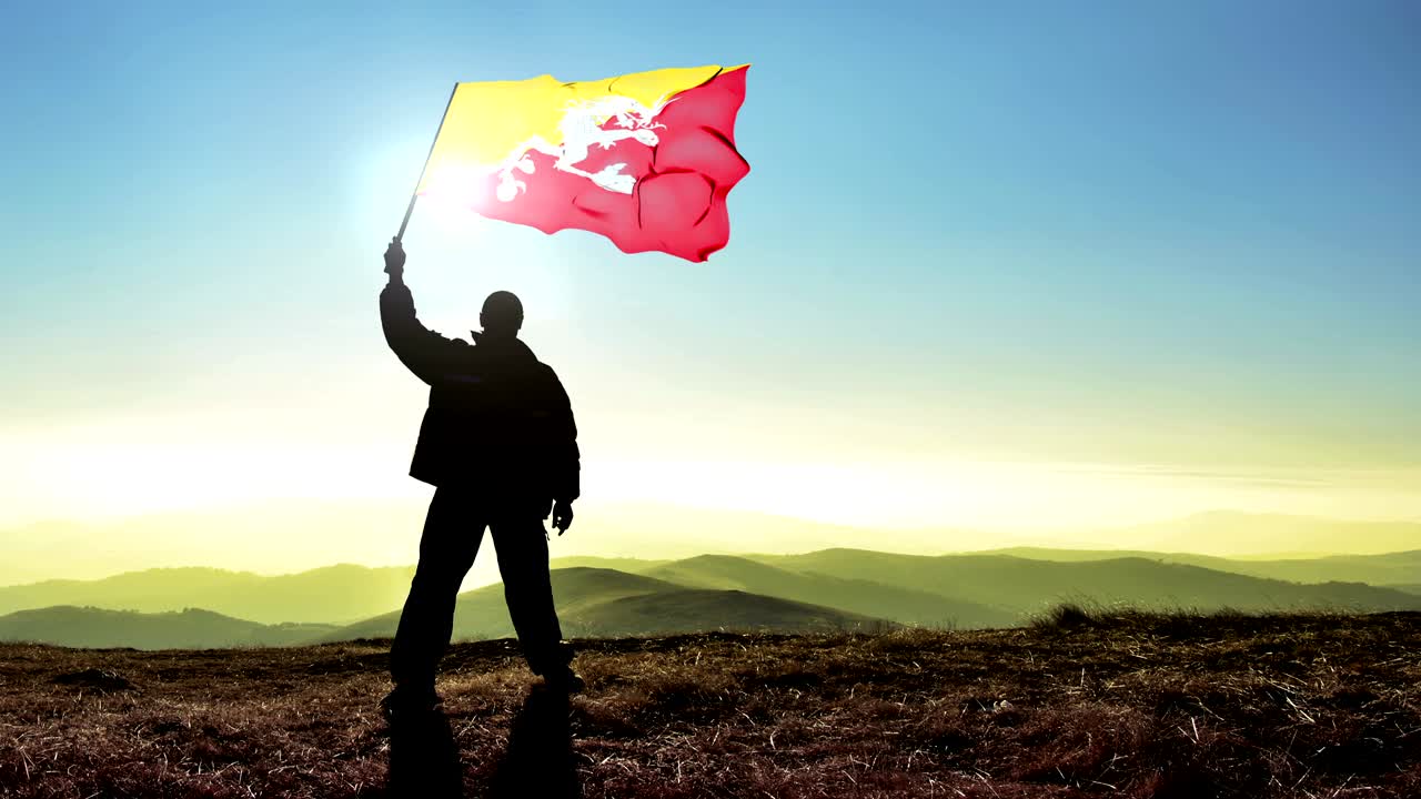 산꼭대기 위에서 부탄 발을 흔들고 있는 성공적인 실루 남자 우승자.