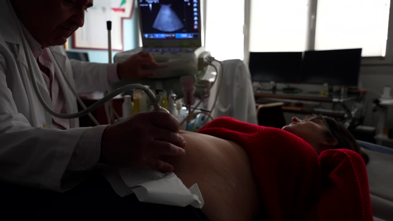 Gynecologist applying gel to pregnant woman's belly in ultrasound scan