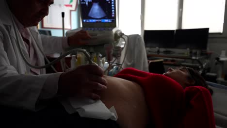 ginecólogo aplicando gel en el vientre de la mujer embarazada en una ecografía