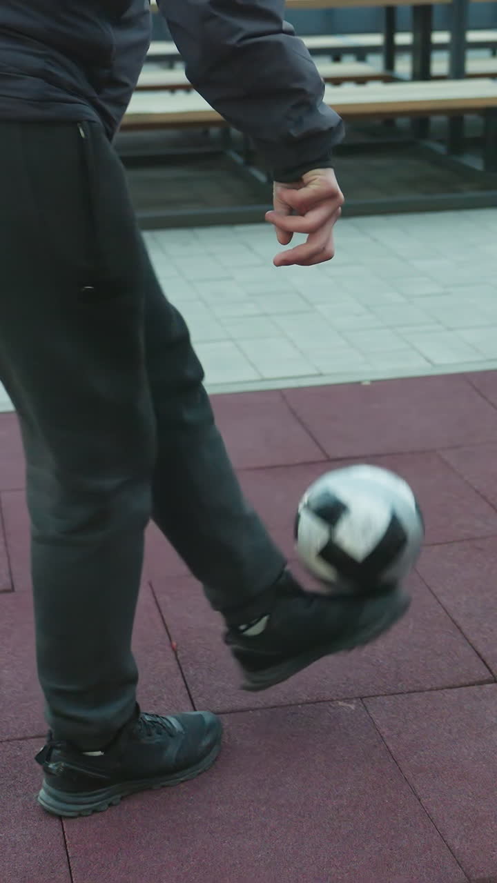 atleta entrenando hábilmente con una pelota de fútbol en la superficie de la arena deportiva, mostrando trabajo de pies y movimiento controlados, el fondo presenta bancos y pisos de azulejos