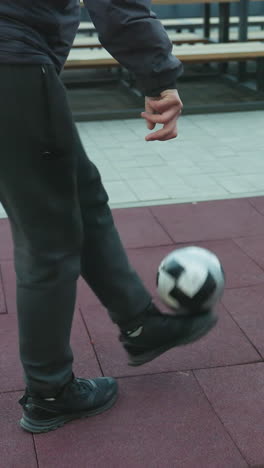 athlete skillfully training with soccer ball on sport arena surface, showcasing controlled footwork and movement, background features benches and tiled flooring