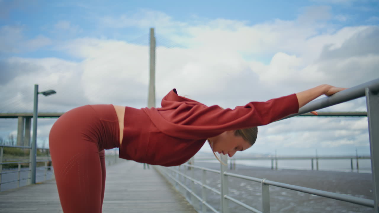 Athletic woman performing exercise at urban bay. Sportswoman bending body warm