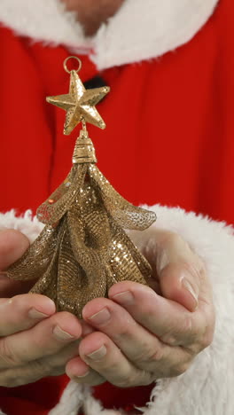 mid-section of santa claus holding christmas ornament