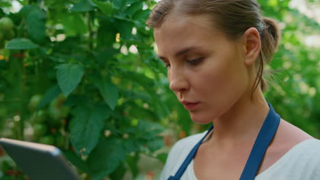 mujer agricultora comprobando la calidad de las plantas con una tableta digital en un primer plano del jardín.