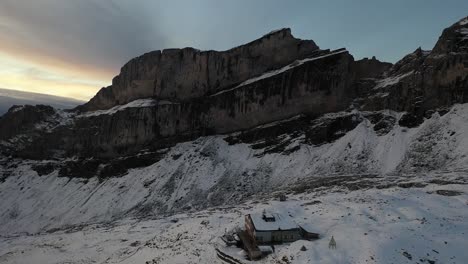 Slow-drone-shot-moving-forwards-above-Rugghubelhutte-with-a-dramatic-sunlit-sky-during-summer-with-lots-of-snow-all-around-the-valley-on-top-of-the-mountain-in-the-Swiss-alps-due-to-high-altitude