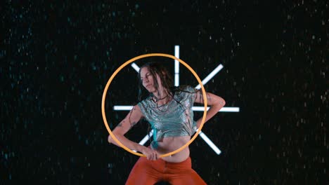 professional female hula hooper elegantly dancing with hula hoop in wet studio