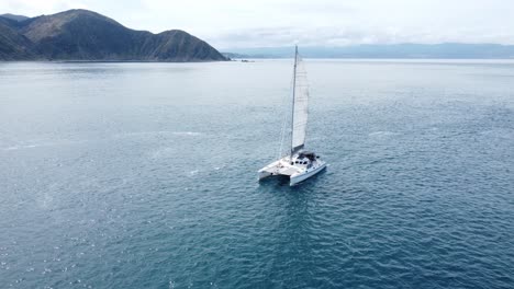 a small yacht sailing past the camera with land in the background