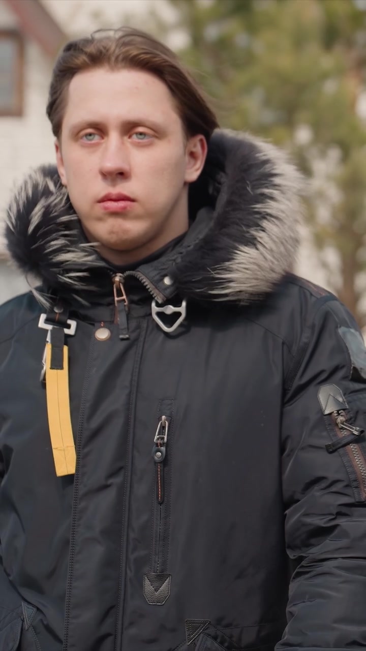 Close up of man wearing dark winter clothing focusing. Subject walks steadily through outdoor urban area. Daylight lighting illuminates scene highlighting textures