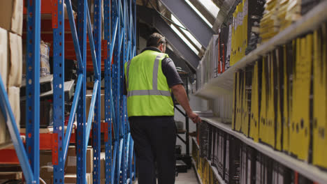 Caucasian-male-factory-worker-at-a-factory-wearing-a-high-vis-vest-inspecting-files