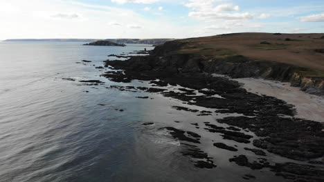 Drone-descends-over-coastline-and-rocky-cliffside-shore,-Thurlestone,-South-Devon-England