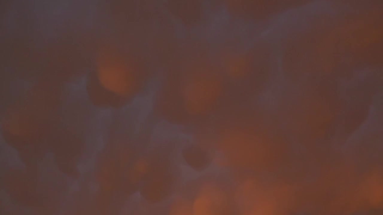 Dark clouds drift across the sky, illuminated by a warm, orange glow. Perfect for atmospheric scenes or weather-related content.