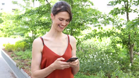 una joven alemana de cabello largo y marrón está escribiendo en su teléfono inteligente o móvil
