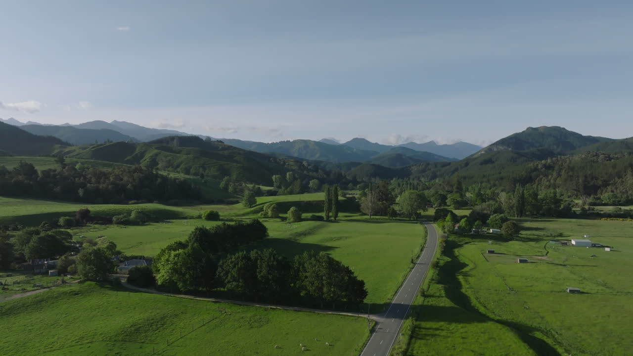 Drone Shot Ascending Over Lush Green Fields with Mountains and Hills in the Distance, New Zealand