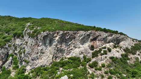 Exuberante-Bosque-Verde-Que-Cubre-Los-Acantilados-De-La-Isla-De-Corfú-En-Grecia-Bajo-Un-Cielo-Despejado,-Vista-Aérea