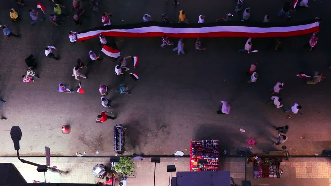 vista desde arriba mirando hacia abajo a los manifestantes que llevan una pancarta y marchan en las calles de el cairo egipto por la noche