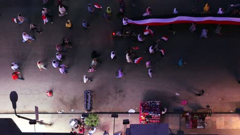 view from overhead looking straight down on protestors carry a banner and march in the streets of cairo egypt at night