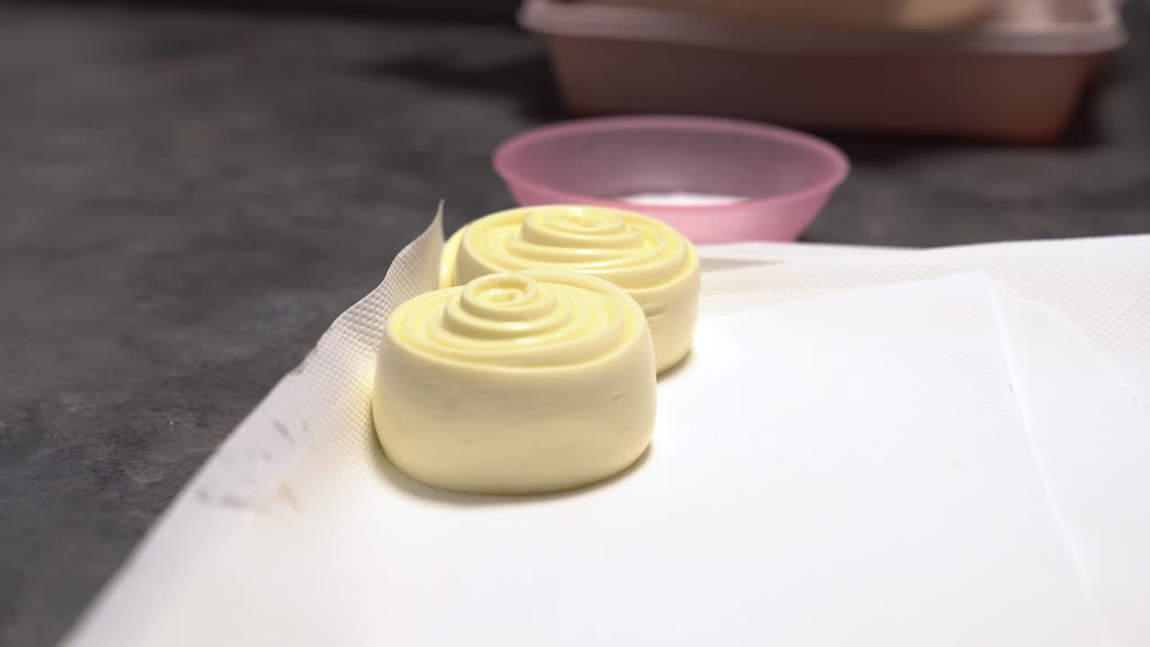 Hands in gloves creating Hungarian Parenyica cheese, featuring swirling shapes. Dairy product