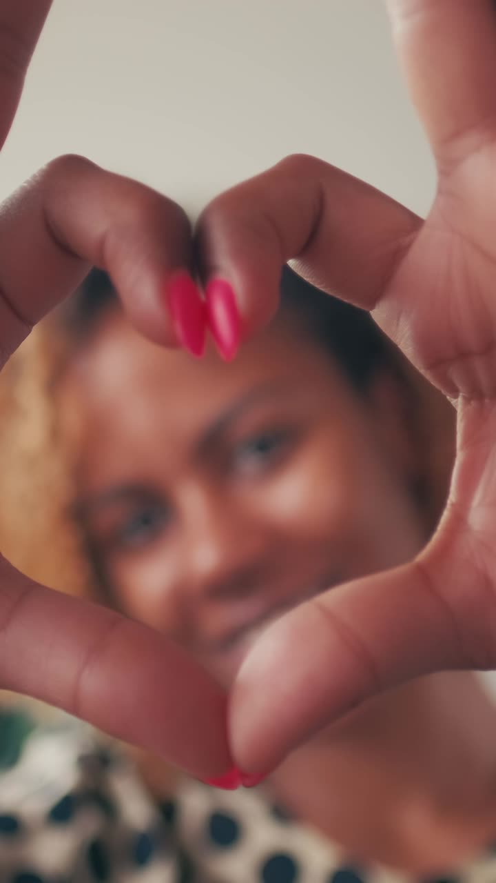 Young beautiful romantic african american woman shows heart gesture from fingers