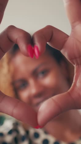 young beautiful romantic african american woman shows heart gesture from fingers